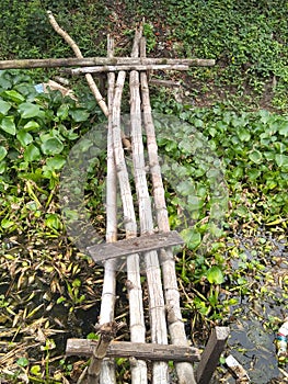 close up photo of a bamboo wooden bridge over a small river for a walking crossing