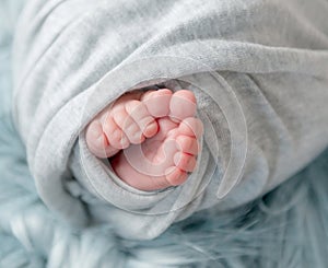 Close-up photo of bare feet of newborn baby in plaid.