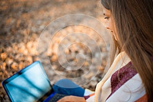 Close-up photo of beautiful girl doing some work on laptop in the park