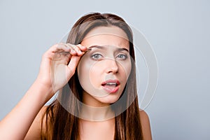 Close up photo of beautiful pretty cute charming woman using tweezers for plucking her eyebrows, isolated on grey background