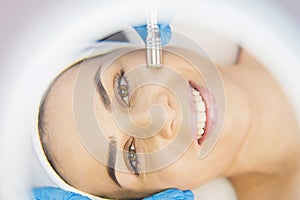 Close up photo of a beautiful smiling woman face looking at the camera through the magnifying glass and enjoying the