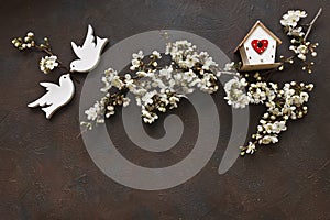 Close-up photo of Beautiful white Flowering Cherry Tree branches with two wooden birds and birdhouse.