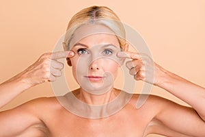 Close up photo of beauty concept aged lady naked shoulders touch eye line blepharoplasty uplift isolated beige color photo