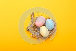 Close up photo of birds nest easter eggs over yellow background