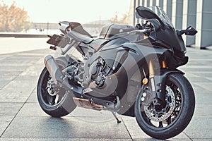 Close-up photo of a black superbike outside near building.