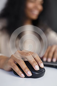 Close up photo of black woman`s hand clicking with mouse while doing work on computer