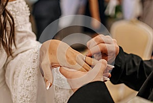 Close-up photo of bride putting a wedding ring on groom& x27;s finger.