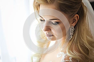 Close up photo of a bride standing in front of the window