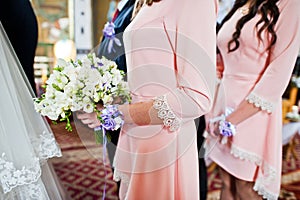 Close-up photo of a bridesmaid holding a bouquet of flowers in t