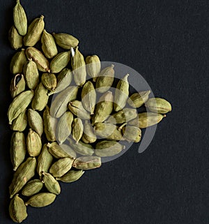 Close up photo of Cardamom pods pile formed as PLAY sign icon on the matt black background. Cardamom is very popular in Indian and