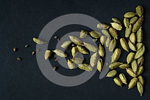 Close up photo of Cardamom pods and seeds pile on the matt black background. It is very popular in Indian and Sri Lanka cuisine