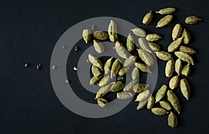 Close up photo of Cardamom pods and seeds pile on the matt black background. It is very popular in Indian and Sri Lanka cuisine