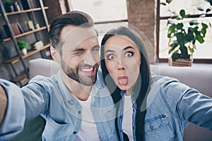 Close up photo of carefree playful positive two people man woman travel trip make selfie show tongue out wink blink sit