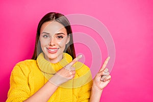 Close up photo of charming youth showing ads with her fingers wearing yellow sweater  over fuchsia background