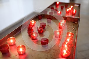 Close-up photo of church candles in red transparent chandeliers