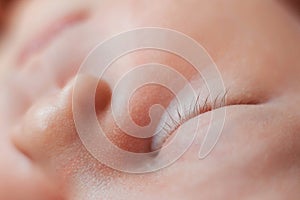 Close-up photo of closed eye of sleeping newborn baby girl.