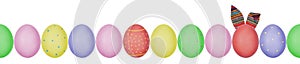 Close up photo of colorful painted Easter eggs with eggshell texture arranged in a row. One egg with textile bunny ears.