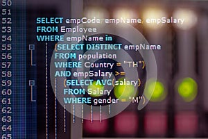 Close-up photo from a computer screen SQL (Structured Query Language) code and server room background.