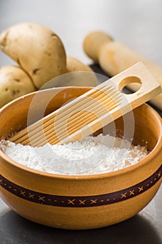 close up photo of cooking ingredients like a bowl of flour, some potatoes and mold of pasta