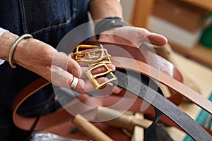 close-up photo of crafstman comparing leather belts during work
