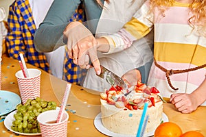 Close-up photo of cropped female hand carving birthday cake