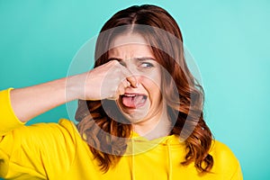 Close up photo of disgusted wavy discontent displeased girl sticking tongue out showing closing her nose isolated over