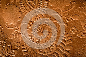 Close up photo of embossed leather with a floral design in rust brown. photo