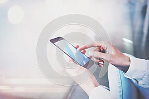 Close up photo of female hands touching screen smartphone. Film effects, blurred background. Horizontal