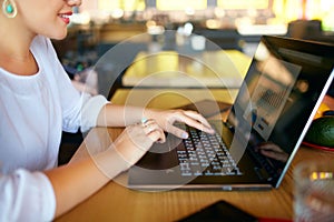 Close-up photo of female hands typing on laptop keyboard and using touchpad. Diagram and charts on screen. Business