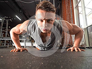 Close up photo of a fitness man doing push ups in gym.