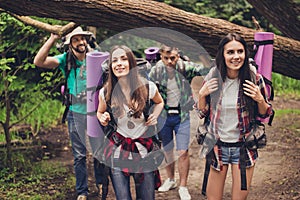 Close up photo of four friends enjoying the beauty of nature, hiking in wild forest, looking for a nice place for camp, smiling, e