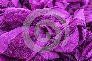 Close-up photo of a fragment of folds of fabric of purple color.