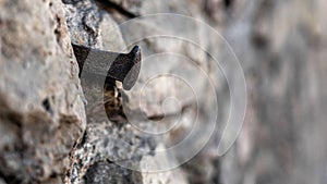 Close-up photo. Fragment of an old masonry wall with a forged iron nail