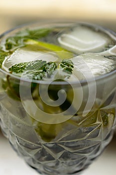 Close up photo of a fresh alcoholic mojito with an ice, lime and mint in the pretty goblet. Background picture.