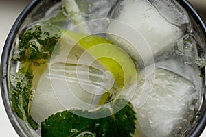 Close up photo of a fresh alcoholic mojito with an ice, lime and mint in the pretty goblet. Background picture.