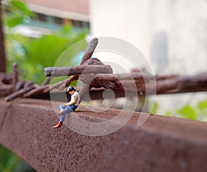 Close Up Photo, Gadget Addicted young Man, Holding Smartphone, sitting at corrosive tower, under barbed wire