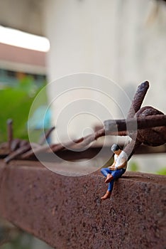 Close Up Photo, Gadget Addicted young Man, Holding Smartphone, sitting at corrosive tower, under barbed wire