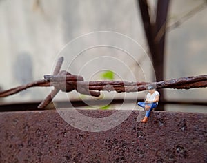 Close Up Photo, Gadget Addicted young Man, Holding Smartphone, sitting at corrosive tower, under barbed wire