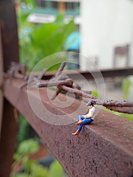 Close Up Photo, Gadget Addicted young Man, Holding Smartphone, sitting at corrosive tower, under barbed wire