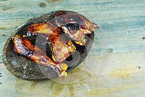 A close up photo of a halved and grilled chicken on a rustic wooden platter