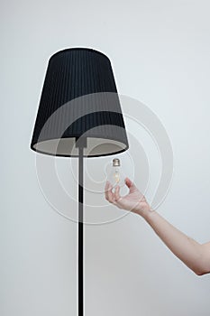 Close-up photo of A hand changes a light bulb in a stylish loft lamp