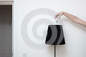 Close-up photo of A hand changes a light bulb in a stylish loft lamp from the top side and doorway near it