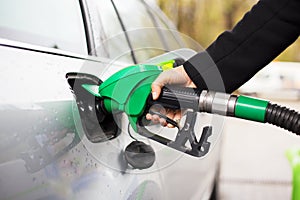 Close-up photo of hand holding fuel pump and refilling car at petrol station photo