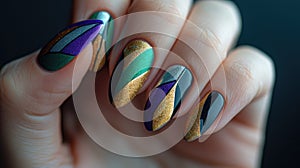 A close-up photo of a hand with Mardi Gras nail art, intricate designs in purple, green, and gold, with swirls, stripes