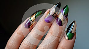 A close-up photo of a hand with Mardi Gras nail art, intricate designs in purple, green, and gold, with swirls, stripes