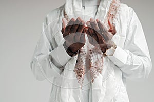 Close up photo. Hands of arab man in white shirt folded together while praying in mosque