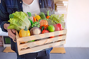 Close-up photo of hands young man is holding a basket box wooden with colorful vegetables and fruits organic to prepare for foods