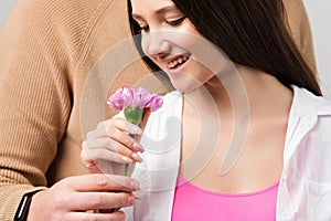 Close up photo of happy smiling pretty girl receiving one flower from her boyfriend wearing smart watch on valentine day