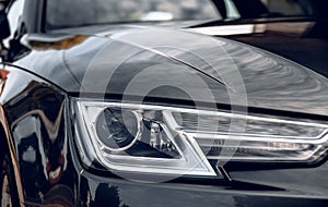 Close-up photo of headlight on dark grey car.