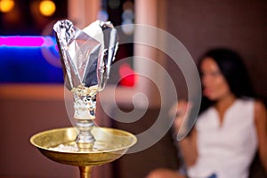 Close-up photo of hookah with smoking girl on background